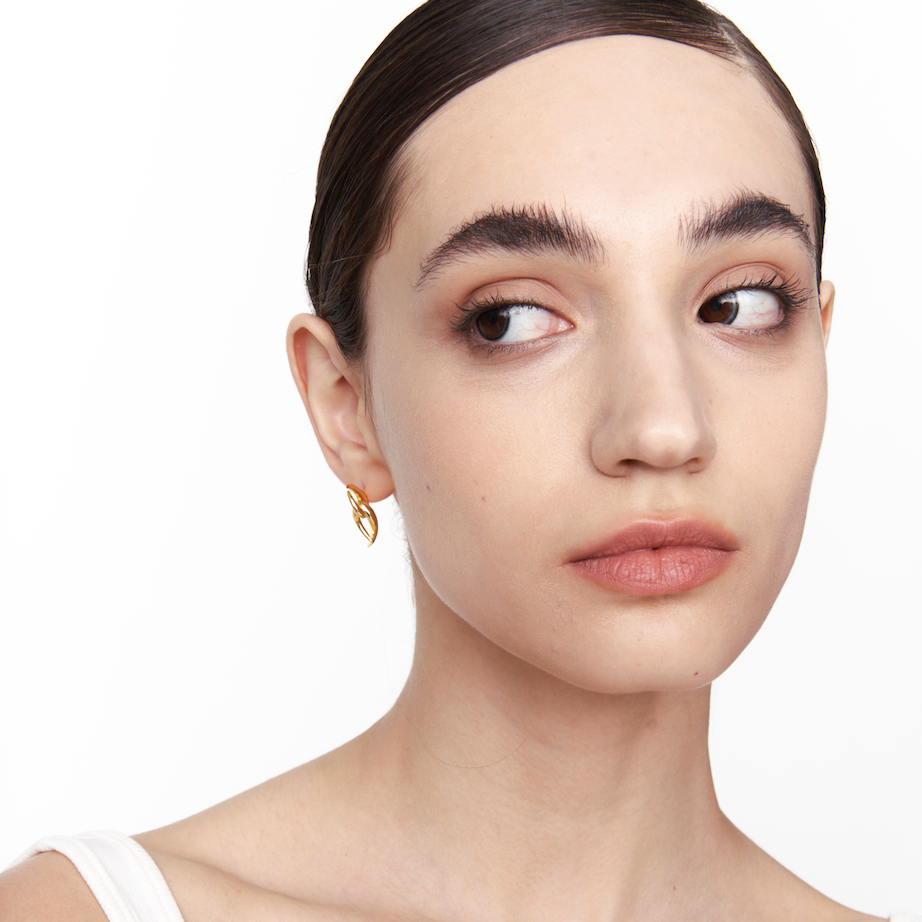 Model wearing Neural Link gold earrings, side view with head turned to the left