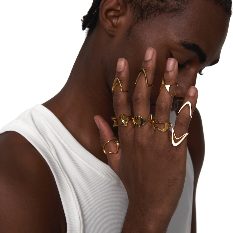 Male model wearing the Sharp Curve Ring in gold, paired with other sculptural rings for a bold cyberpunk-inspired look.