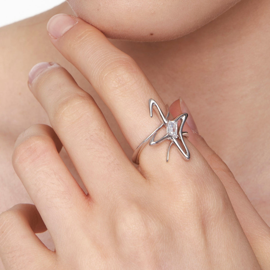 Futuristic silver star ring with an emerald-cut zircon at the center, featuring sculptural lines and a cosmic-inspired design