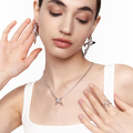 Model wearing matching silver jewelry set including angular earrings, star-shaped ring, and pendant necklace, styled with a white tank top against a white background








