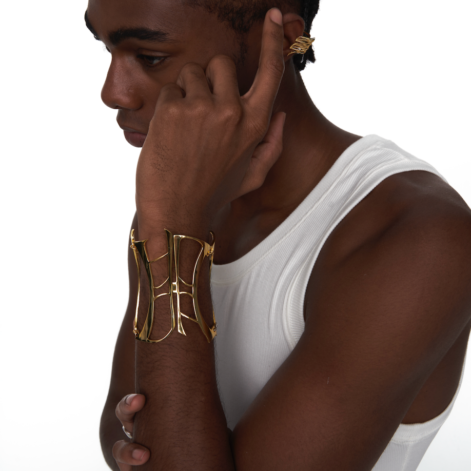 Gold sculptural bracelet styled on male model’s arm in side profile