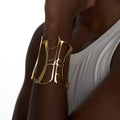 Gold corset cuff bracelet styled on model’s forearm against white tank top