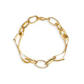 Sculptural gold bracelet with wave-like links on white background