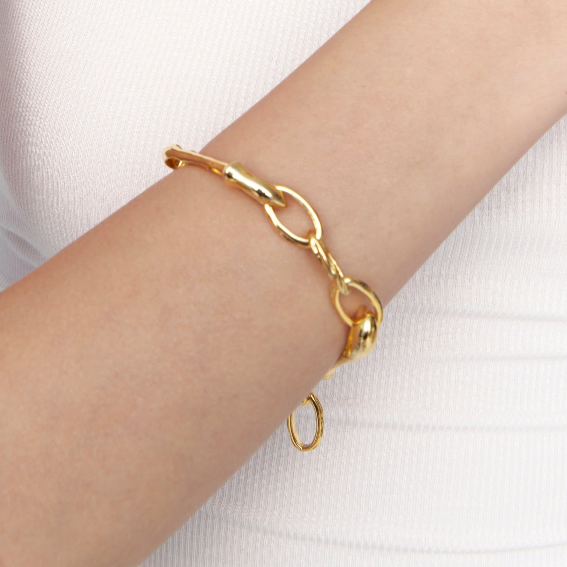 Gold sculptural bracelet worn on wrist, close-up view on model
