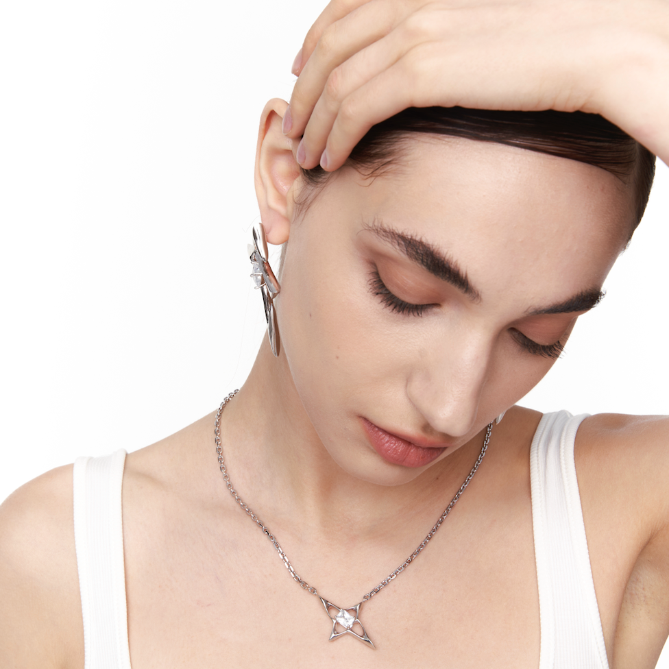 Model wearing a silver geometric star necklace with faceted center stone. 925 sterling silver pendant styled with minimalist fashion, inspired by celestial aesthetics.
