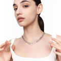 Model adjusting My Heart Soars silver V-link necklace, a chunky sculptural chain resting above the collarbone