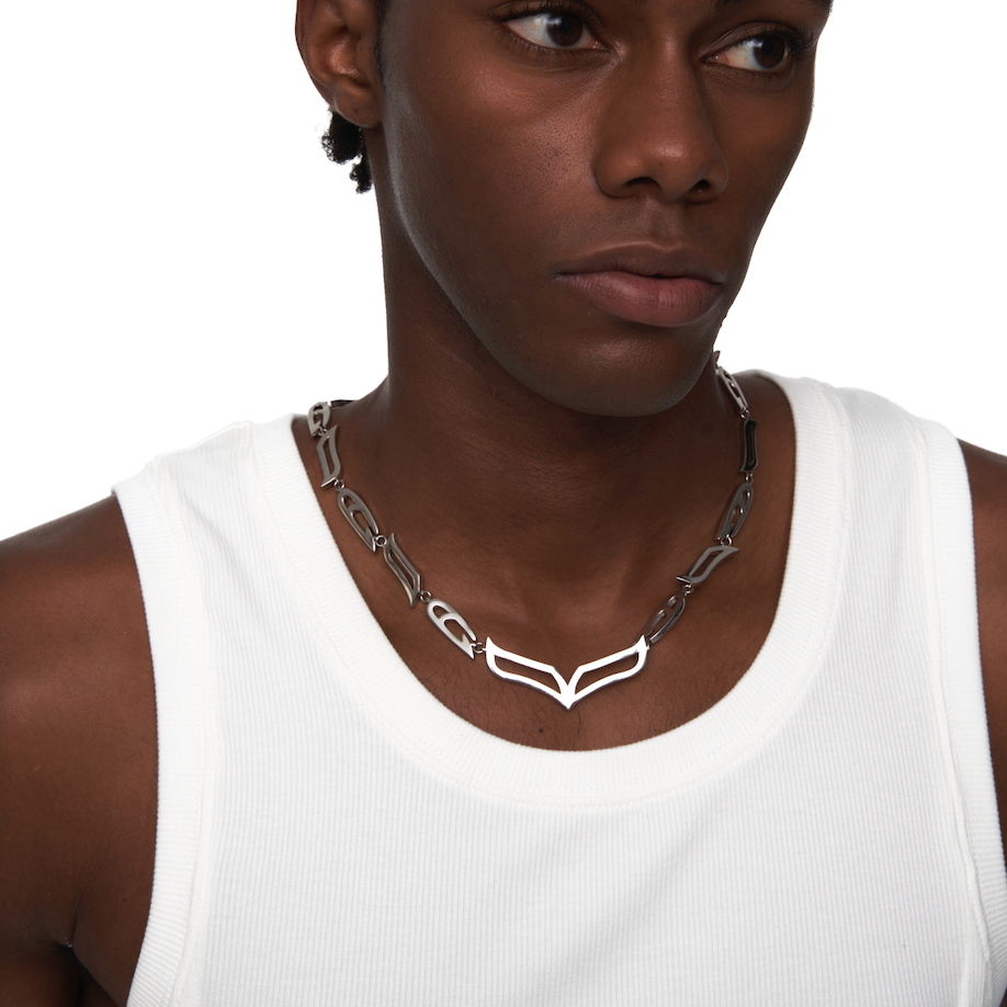Male model wearing the My Heart Soars chunky silver V-link necklace, styled over a white tank top for a genderless, futuristic look