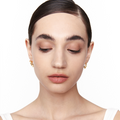 Model wearing Neural Link gold sculptural earrings, front-facing view with eyes closed