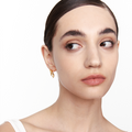Model wearing Neural Link gold earrings, side view with head turned to the left