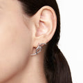 Model wearing futuristic silver neural-inspired earring with aerodynamic arc design