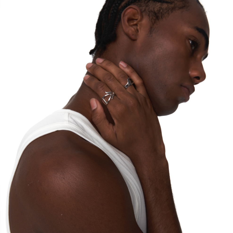 Model wearing two sculptural silver rings from Outsider Artist, featuring abstract open-form designs, styled on the middle and ring fingers.