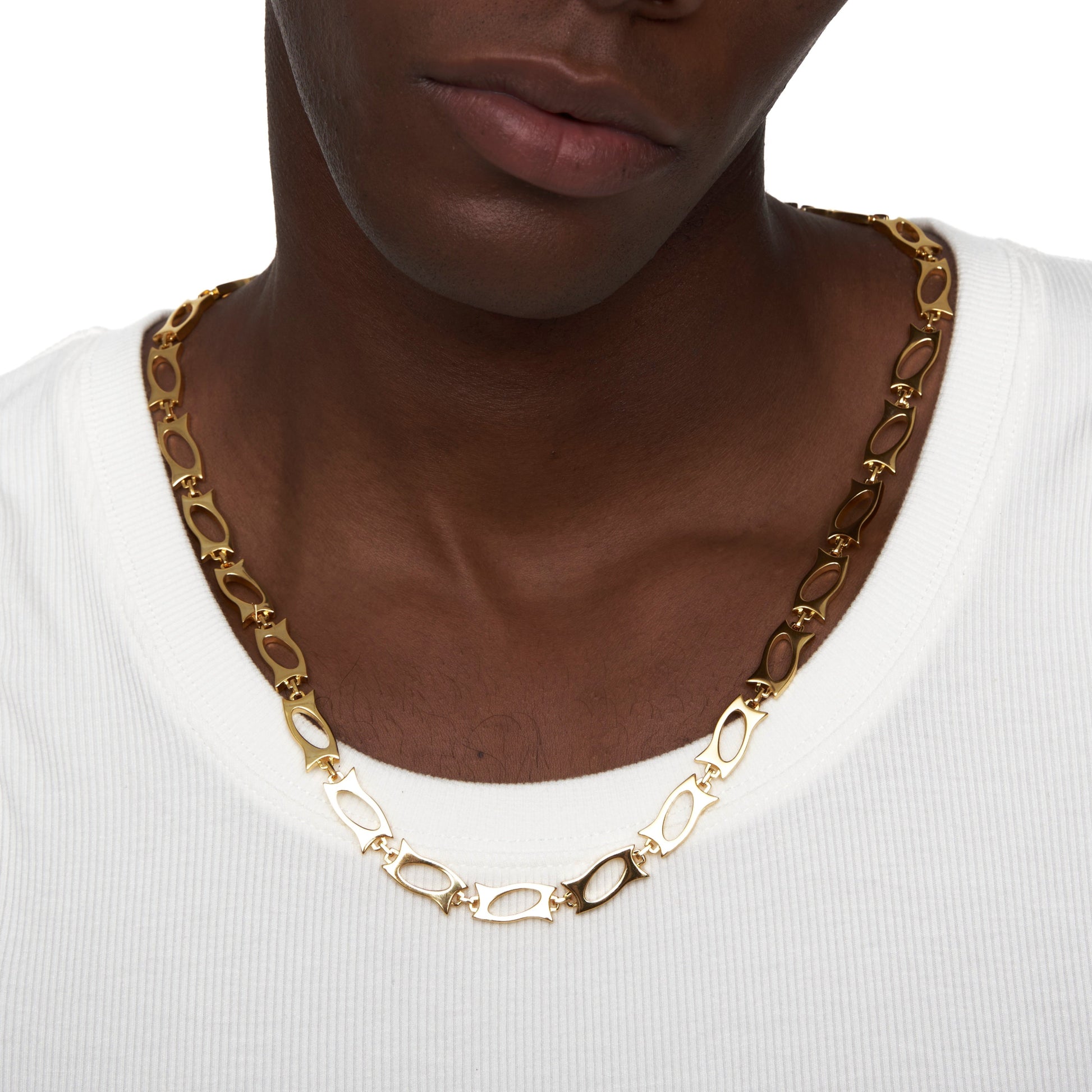Close-up of gold blade segment necklace worn over white shirt