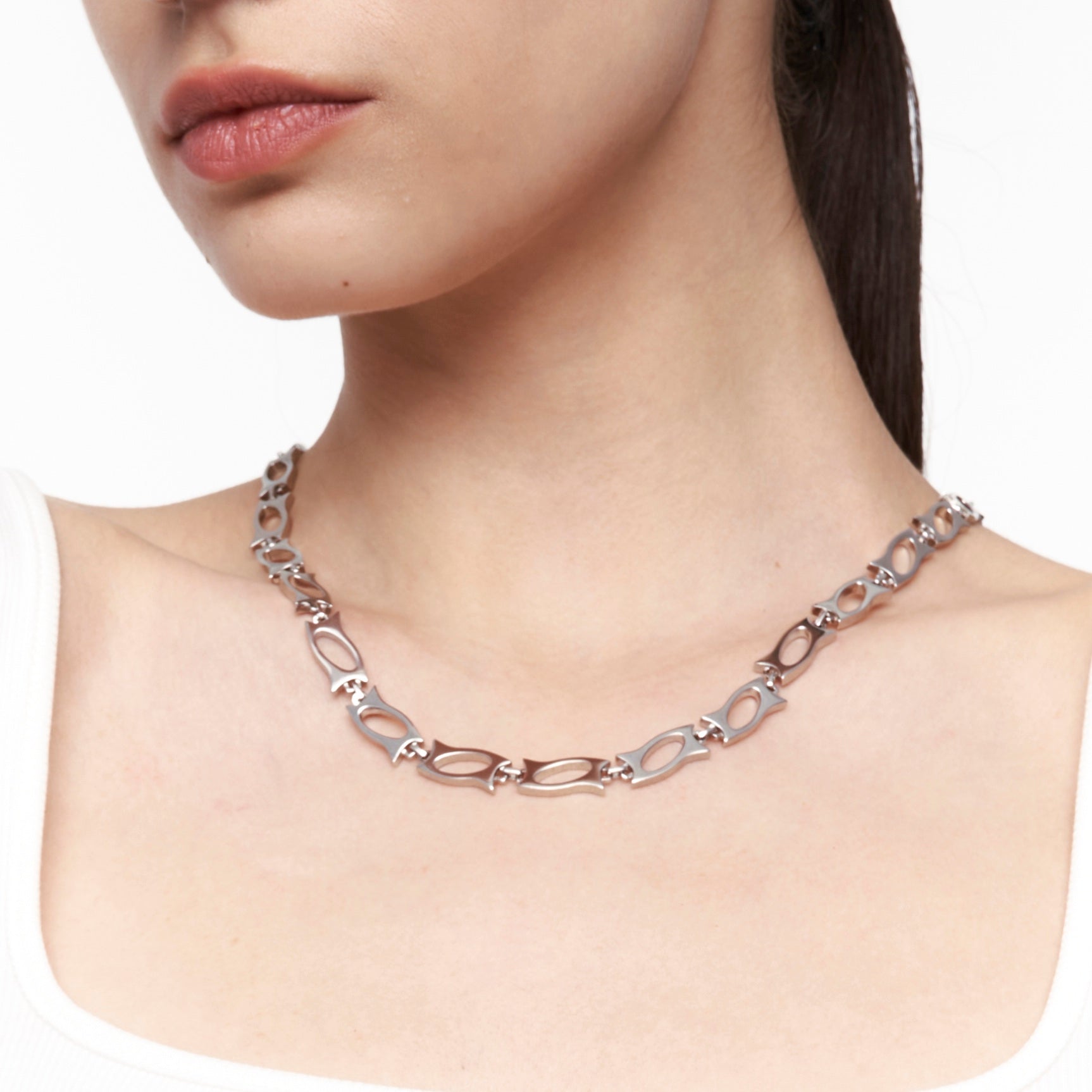 Close-up of silver blade segment necklace worn on model’s neck