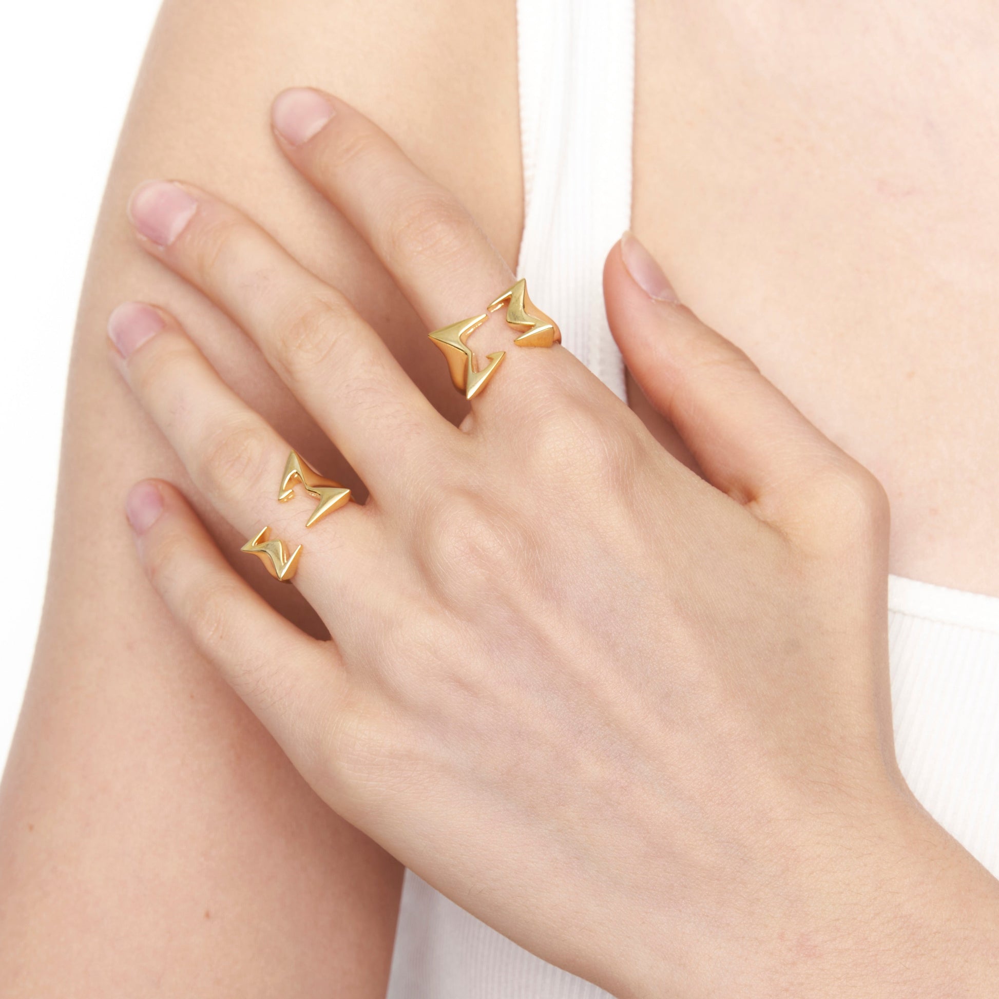 Model wearing stacked gold star rings on index and middle fingers

