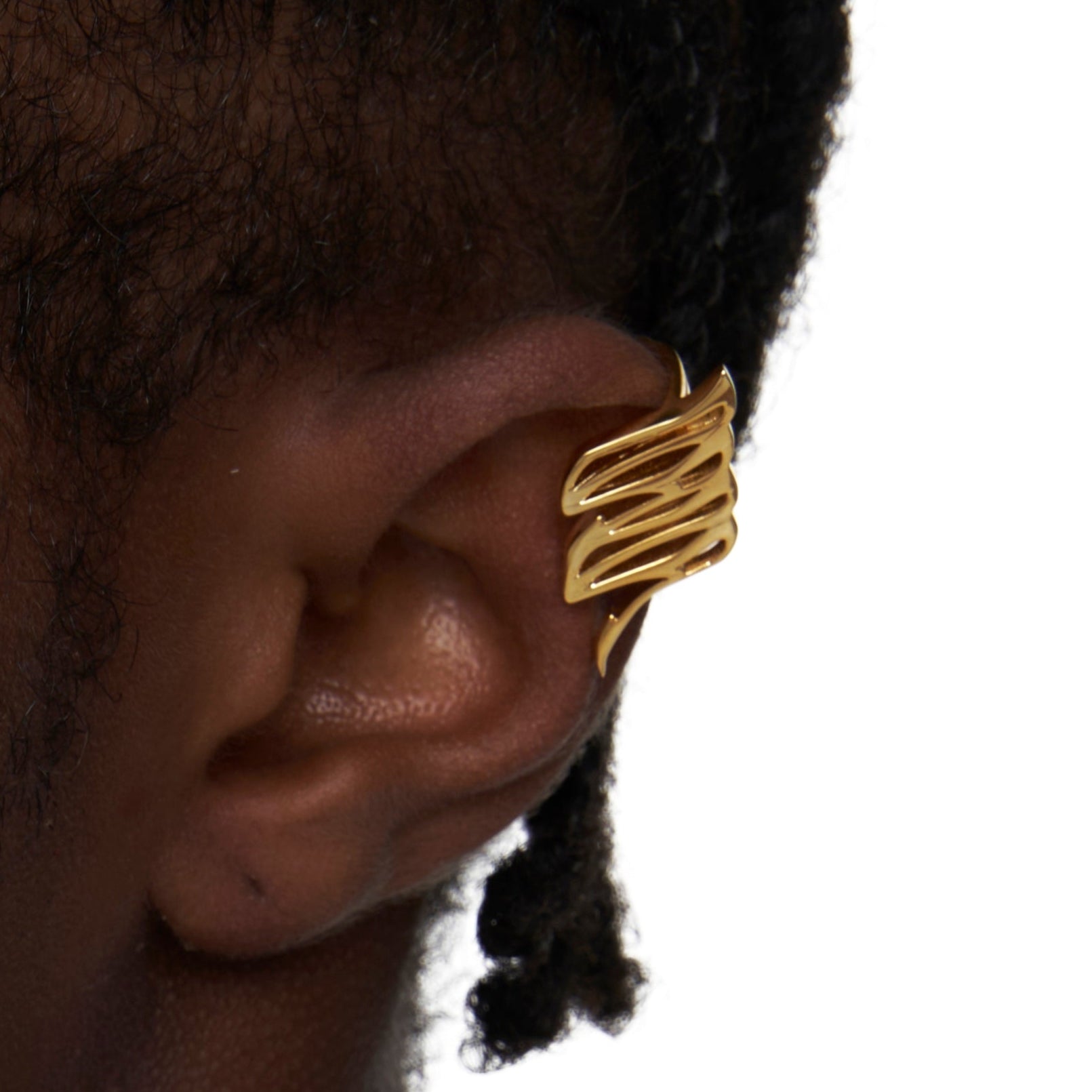 Gold aerodynamic ear cuff styled on model's ear, no piercing needed