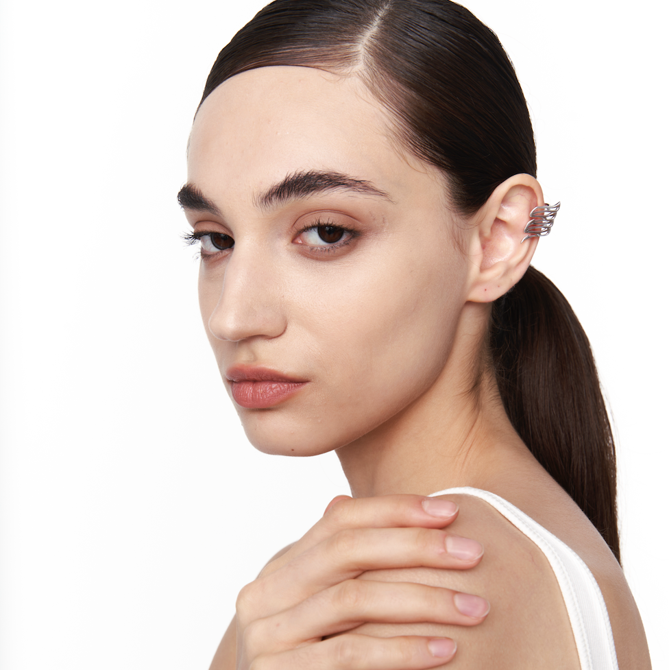 Model wearing aerodynamic 925 silver wing ear cuff with sculptural design, worn without piercing.

