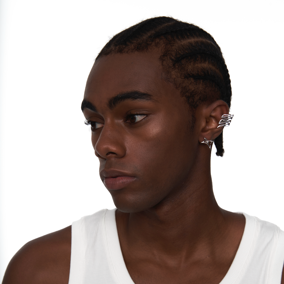 Sculptural silver wing ear cuff styled on model's right ear, worn without piercing